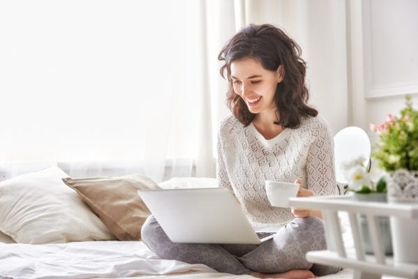Woman in cozy clothes watching Netflix in bed on a cold winter morning