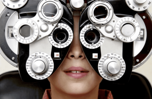 Woman taking a refractory eye exam on an autorefractor to get her new contact lens prescription