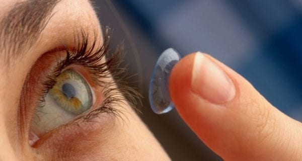 Woman about to put a contact lens in her eye after having cleaned it
