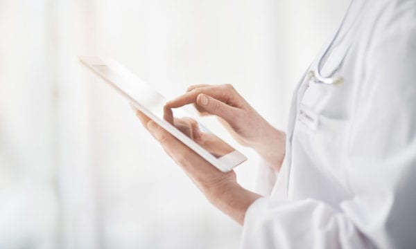 Close up of optometrist using an iPad to look at a patient's electronic medical records to diagnose their eye condition