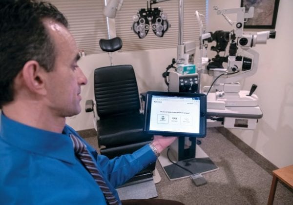 Optometrist showing his patient how to take an online eye exam